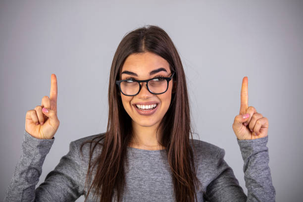 istock Pretty young female shows something above her head 1311243531