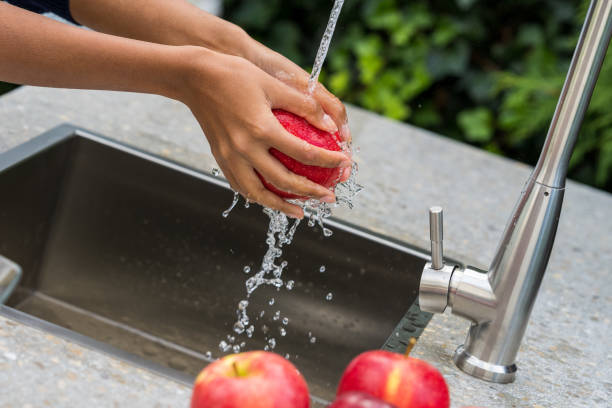 Woman's hands washing apples in garden sink