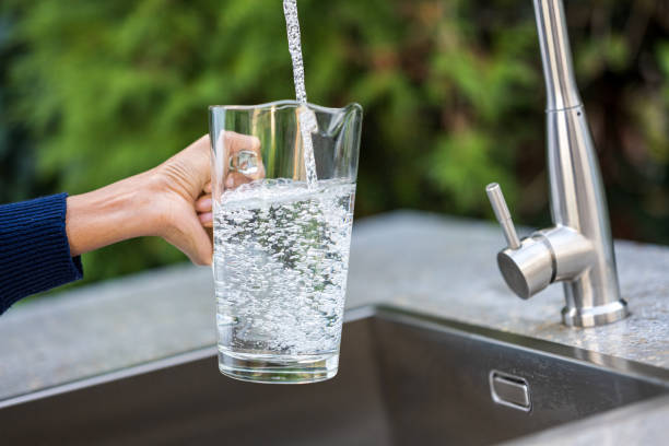 istock Woman's hands filling glass with water 1311244584
