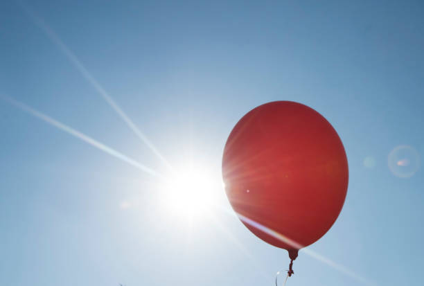 istock red balloon and blue sky background with sun 1311245162