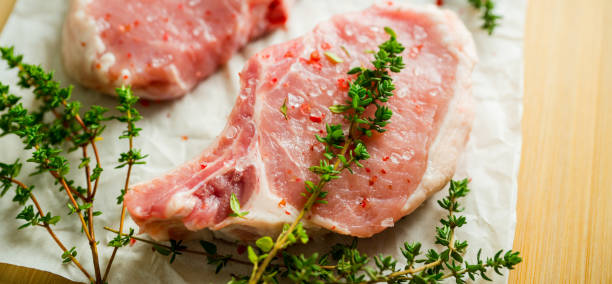 istock Raw pork meat with thyme and spices on the rustic background. Selective focus. Shallow depth of field. 1311247645