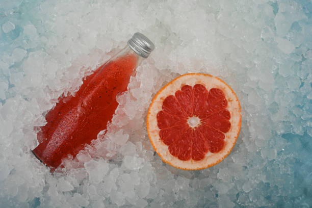 氷の上の赤いグレープフルーツドリンクのボトル - crushed ice colors grape fruit ストックフォトと画像