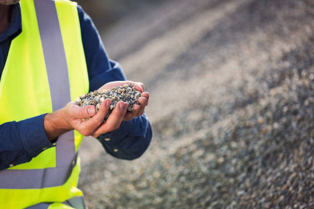 Gravel quality control Open-pit mine engineer wearing protective clothes holding gravel in hands. Quality control concept.Close up of hands, unrecognizable person. gravel mound stock pictures, royalty-free photos & images