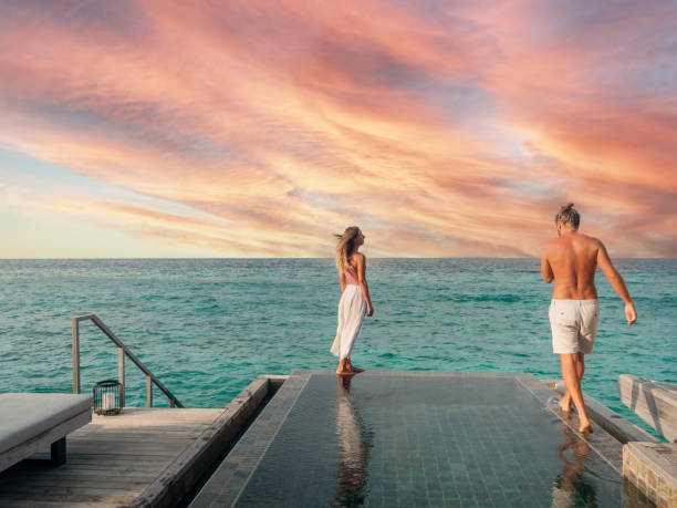 istock Couple walking at the edge of infinity pool at sunset 1311257876