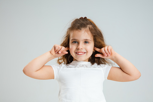 Little girl brushing her hair with hair brush, white background with copy space, close-up