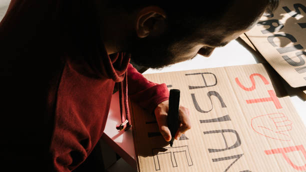 istock Man drawing posters protest against racism at home 1311260003