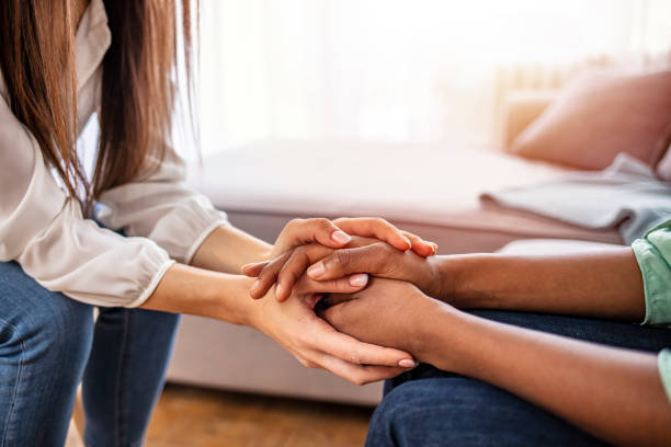 Different ethnicity female friends hold hands during confidential talk close up