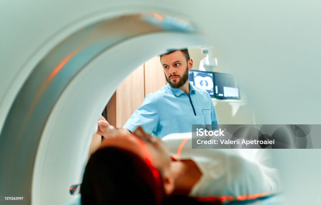 Doctor team A patient lying on CT or MRI, the bed moves inside the machine, scanning her body and brain under the supervision of a doctor and a radiologist. In a medical laboratory with high-tech equipment. MRI Scan Stock Photo