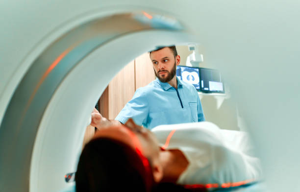 Doctor team A patient lying on CT or MRI, the bed moves inside the machine, scanning her body and brain under the supervision of a doctor and a radiologist. In a medical laboratory with high-tech equipment. mri scanner photos stock pictures, royalty-free photos & images