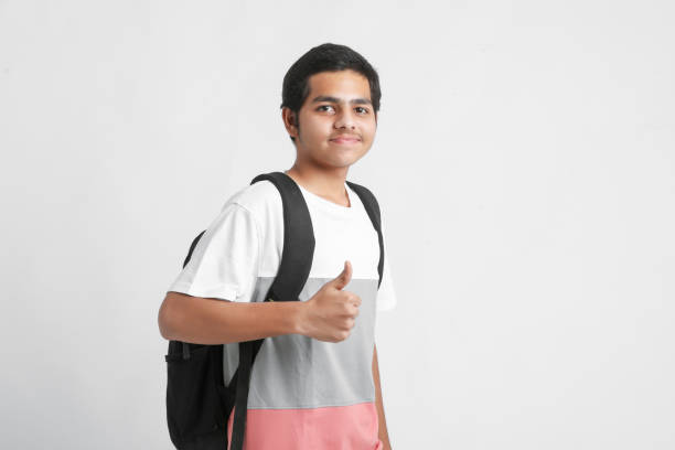 young indian college student holding bag on white background. - thumps up imagens e fotografias de stock