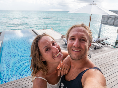 30's couple taking selfie photo over sea in luxury private villa in the Maldives Islands