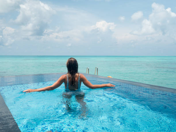 istock Woman relaxes inside infinity pool over reef lagoon 1311266502