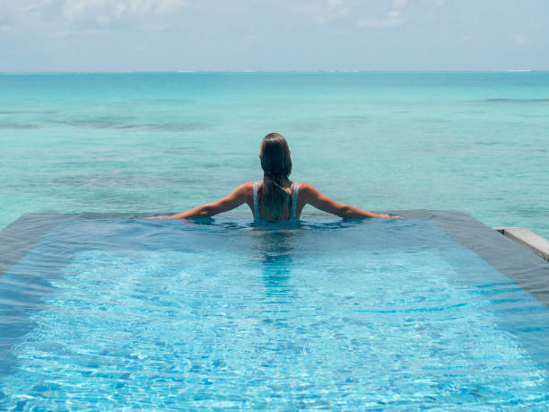 istock Woman relaxes inside infinity pool over reef lagoon 1311266679