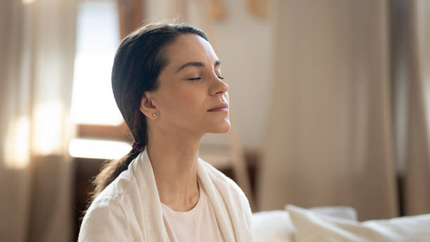 fermez-vous vers le haut de la femme paisible avec les yeux fermés méditant à la maison - visage femme apaisement photos et images de collection