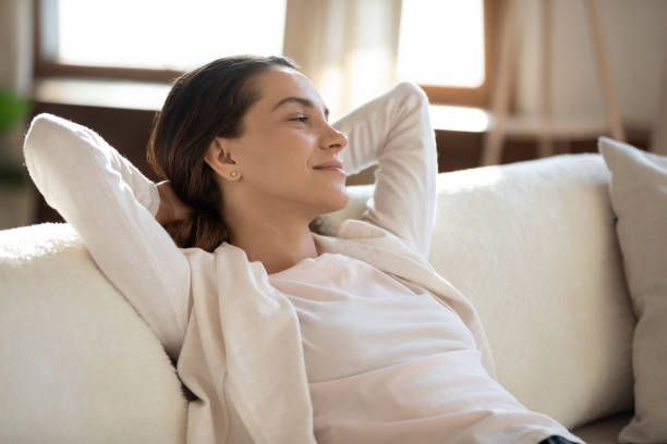 istock Close up dreamy smiling woman daydreaming, stretching on sofa 1311266828