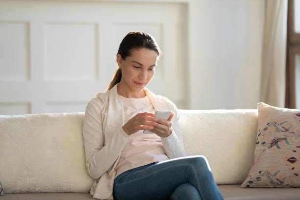 istock Close up attractive young woman using phone, sitting on couch 1311266829
