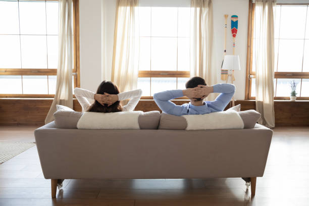 istock Rear view young couple relaxing on couch in modern apartment 1311267357
