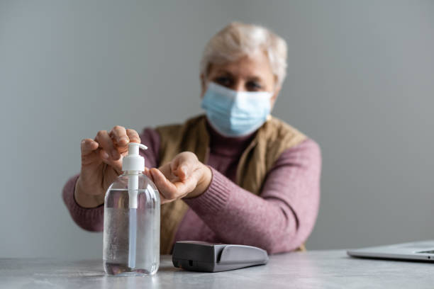 istock Elderly woman sanitizing her hands with alcohol gel 1311269341