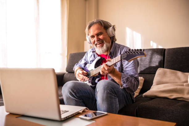 istock A man learns to play electric guitar from his living room through e-learning on his laptop. 1311269745