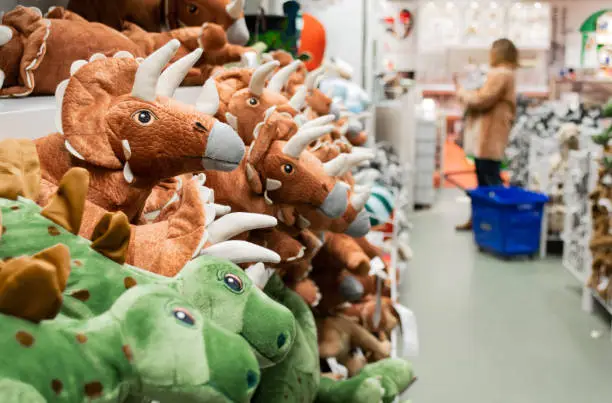 Photo of Close-up of toy dinosaurs on store shelves. Blurry shoppers in the background