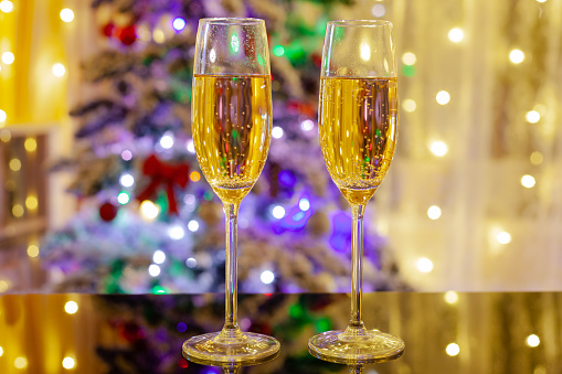 two glasses of champagne on the background of the Christmas tree, a Christmas card, used as a background or texture