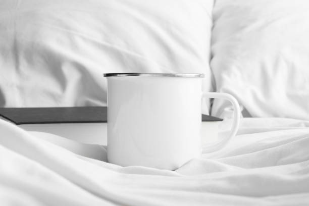 istock Enamel mug mockup with a book on the bed. 1311277917