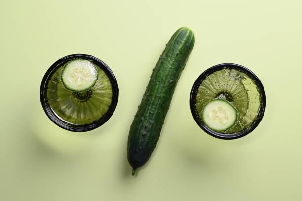 istock Stylish glass goblets with water with cucumber slices in sunlight 1311279211
