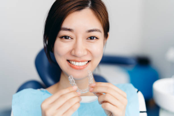 Asian young attractive woman holding orthodontic retainers in dental clinic. Invisalign orthodontics concept. Dental Aligner, Dental Braces, Smiling, China - East Asia, Korea, Japanese Culture braces stock pictures, royalty-free photos & images