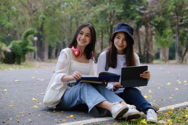 istock Two students are sitting in university during reading a book and communication. Study, education, university, college, graduate concept. 1311280412