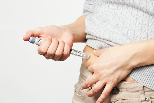 Young woman doing insulin injection pen, close-up. Diabetic patient with insulin pen for control diabetes.