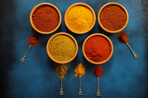 Curry Turmeric Paprika and Masala Powders on blue background, ingredients towards Indian Cuisine