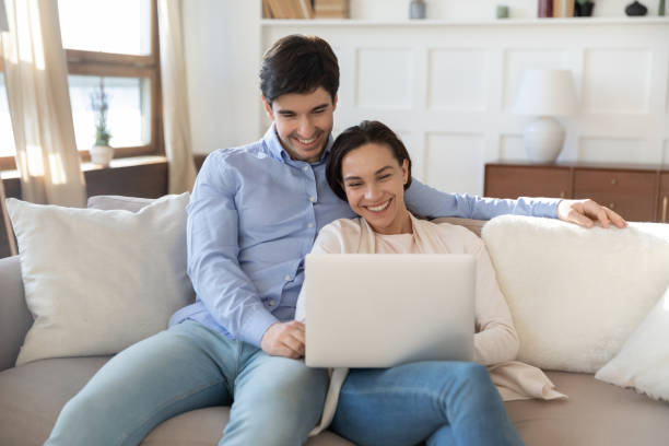 istock Happy young couple using laptop, relaxing on couch together 1311283482
