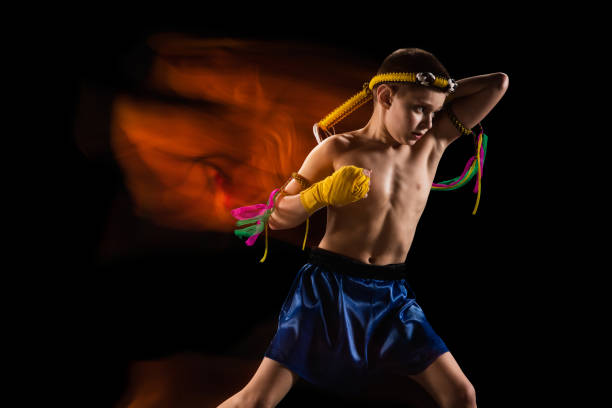 istock Little boy exercising thai boxing on black background. Fighter practicing, training in martial arts in action, motion. Evolution of movement, catching moment. 1311286144