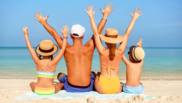 istock Loving family resting and raising arm on exotic seashore 1311286473