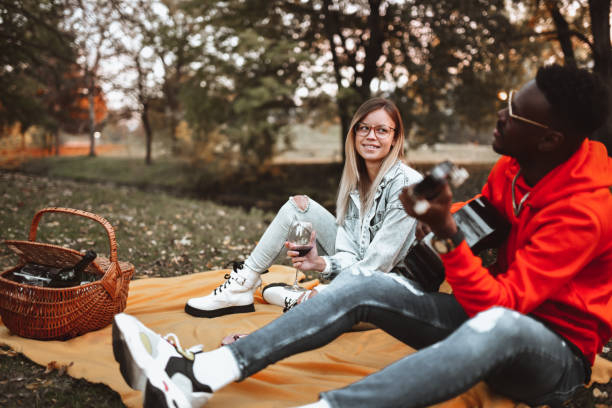 istock Modern African Musician Plays Guitar For Girlfriend In Park 1311286636