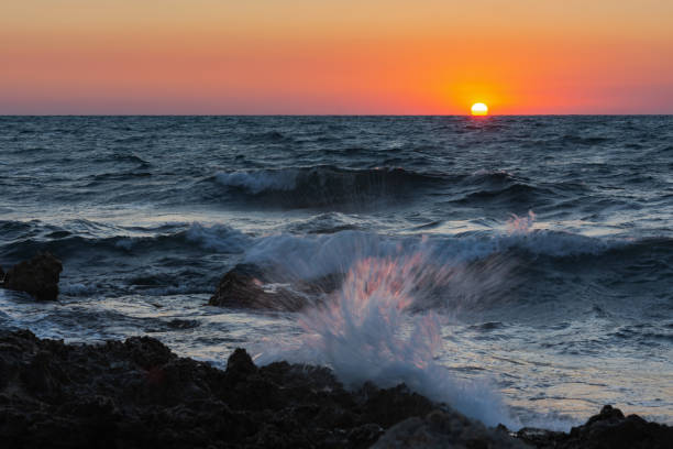 Sunset and storm at sea. Big waves against the setting sun.