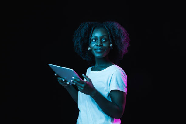 istock Young African-American girl using tablet isolated on dark background in neon. 1311287629