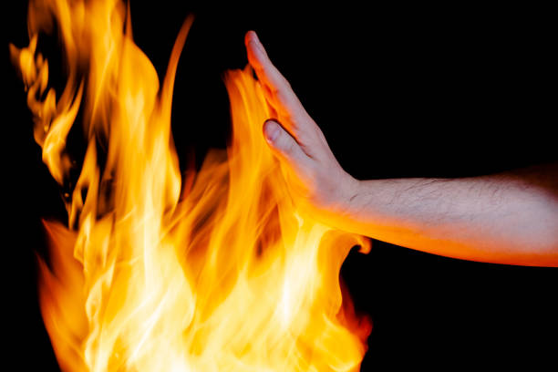istock mans hand touches the flame, place under the text 1311288229