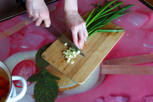 Woman cuts green onions on a cutting board