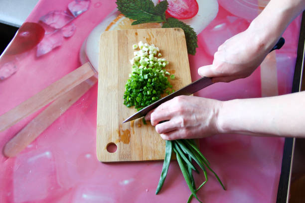 Woman cuts green onions on a cutting board