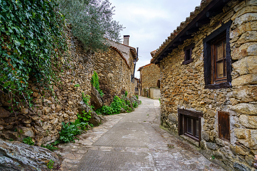 Narrow alley in an old medieval town made of stone in the Sierra de Madrid. Horcajuelo. Spain.