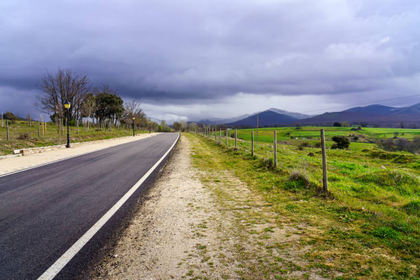 istock Asphalt road leading to mountains with dark storm cloud sky. 1311289339