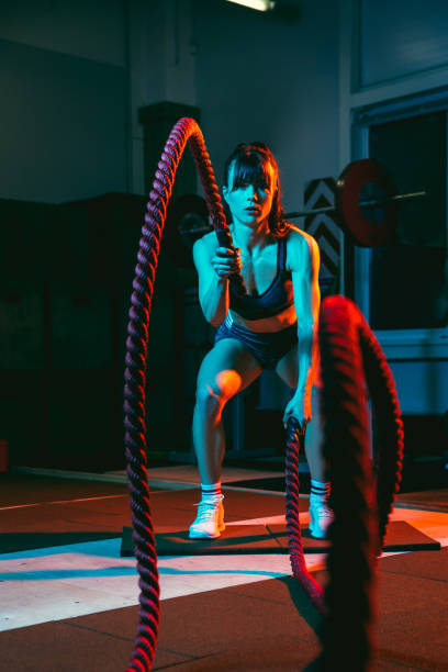 junge athletische frau, fitness-trainer-training im fitnessstudio in gemischtem neonlicht. - rope way stock-fotos und bilder