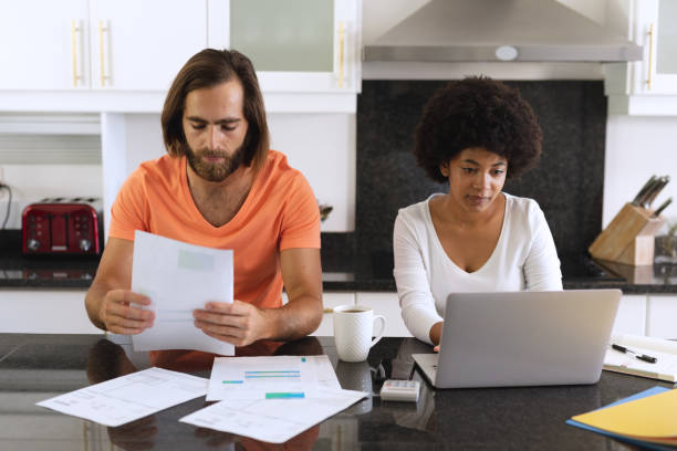 istock Diverse couple sitting in kitchen using laptop and paying bills 1311290189