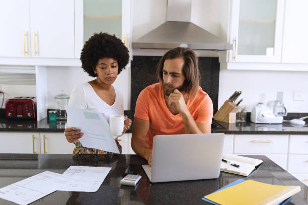 istock Diverse couple sitting in kitchen using laptop and paying bills 1311290250