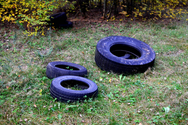 old rubber tires from a car are thrown into the forest. people pollute the environment harming nature - harming imagens e fotografias de stock