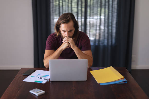 istock Worried caucasian man sitting at table working from home and looking at laptop screen 1311291434