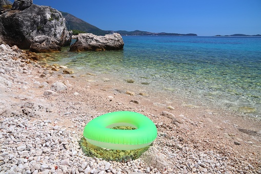 Mlini beach in Croatia. Dalmatia region Adriatic Sea coast. Inflatable wheel float toy.
