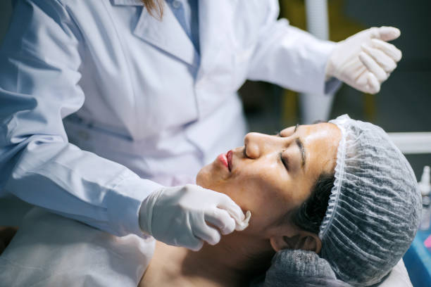 mujeres asiáticas chinas cosmetólogas limpiando su cara de cliente con bola de algodón antes de que la operación comience en la sala de cirugía - scrub brush fotos fotografías e imágenes de stock