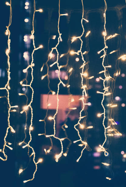 istock Glowing electric garlands on the night window, beautiful bright abstract celebration background and texture. Vertical shot 1311294941
